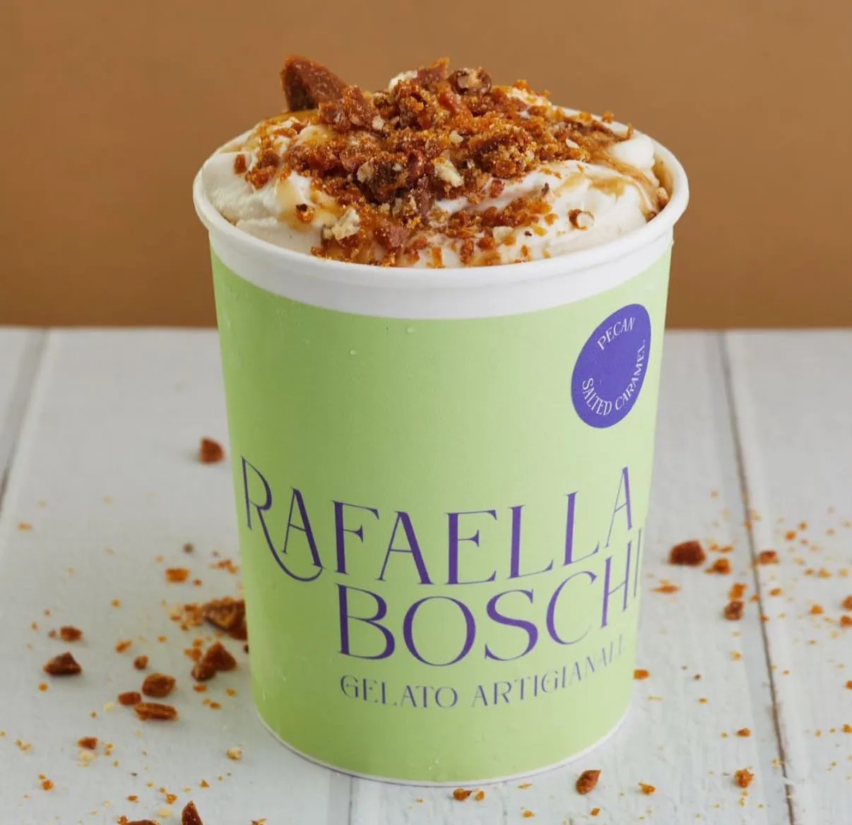 Pote de gelato de caramelo salado cubierto con crema batida, caramelo y pecanas garapiñadas