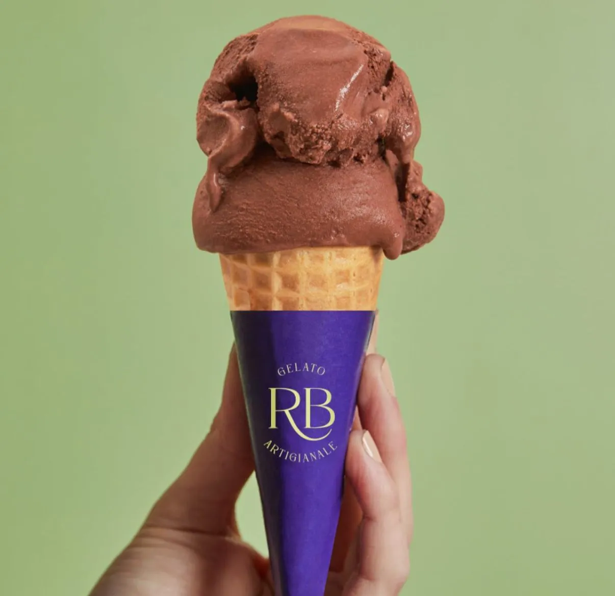 Cono de gelato de chocolate bitter con envoltura violeta de la marca, sobre fondo verde