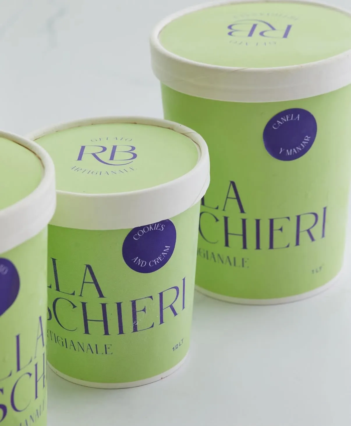 Potes de gelato canela y manjar y cookies and cream sobre una superficie blanca